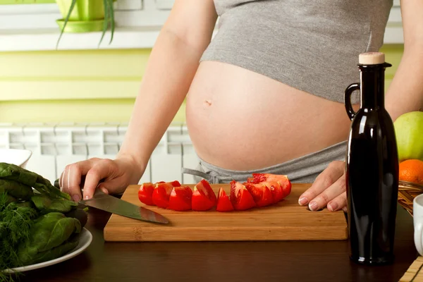 Mujer embarazada en la cocina Imagen de archivo