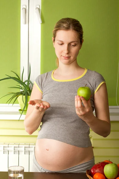 Hamile kadın hapları ve apple arasında seçim yapma — Stok fotoğraf