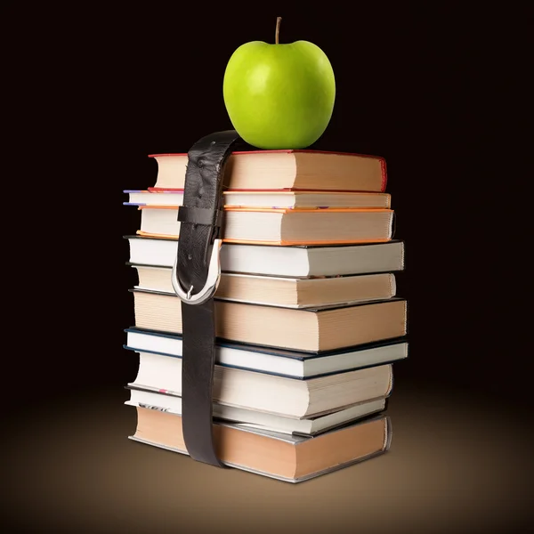 Livros pilha com cinto e maçã — Fotografia de Stock