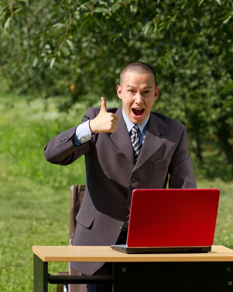 Homem com laptop vermelho trabalhando ao ar livre — Fotografia de Stock