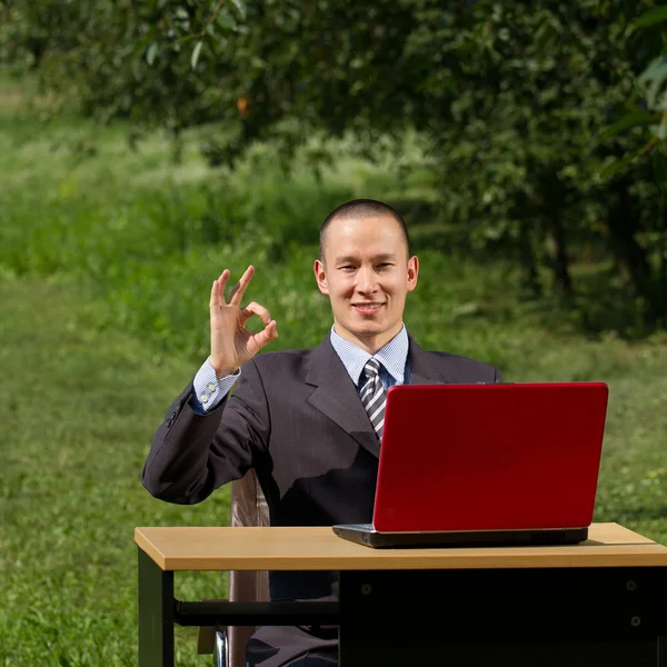 Adam açık havada çalışan kırmızı dizüstü bilgisayar ile — Stok fotoğraf
