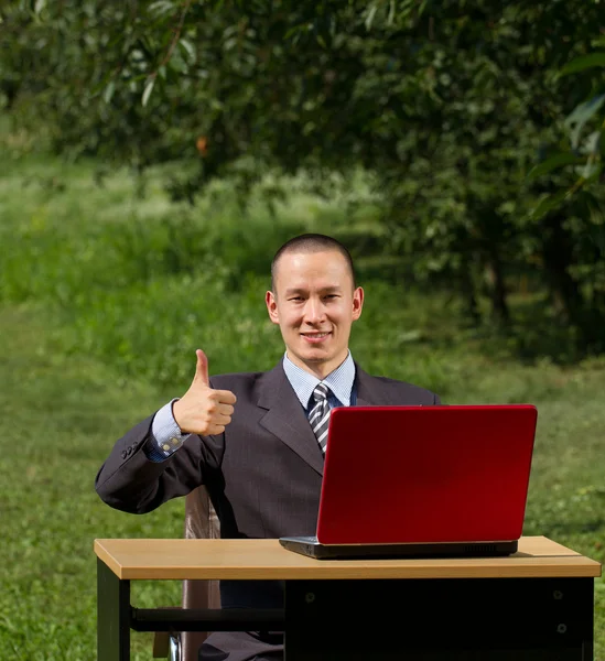 Man met rode laptop buitenshuis werken — Stockfoto