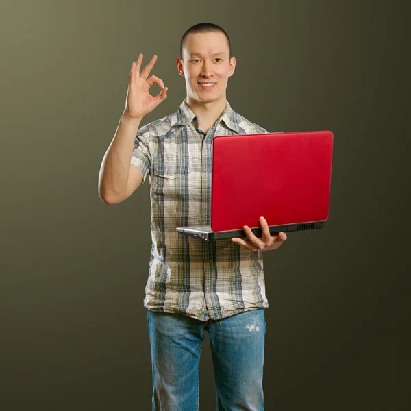 Asiático macho com laptop em suas mãos mostra OK — Fotografia de Stock