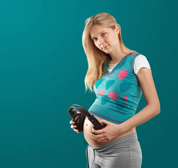 Беременная женщина с наушниками — стоковое фото