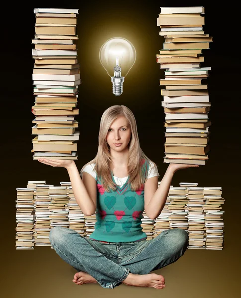 Vrouw in lotus poseren met vele boeken in haar handen en lamp — Stockfoto