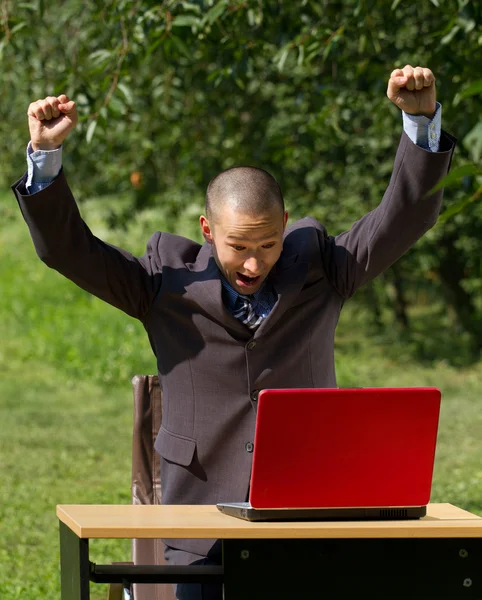 Hombre con portátil rojo trabajando al aire libre — Foto de Stock