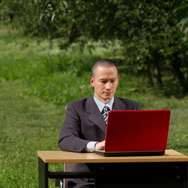Mann mit rotem Laptop arbeitet im Freien — Stockfoto