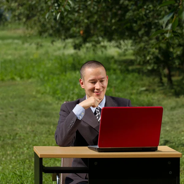 Hombre con portátil rojo trabajando al aire libre — Foto de Stock