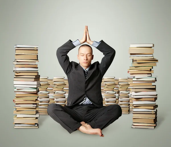 Empresario en pose de loto con muchos libros cerca — Foto de Stock