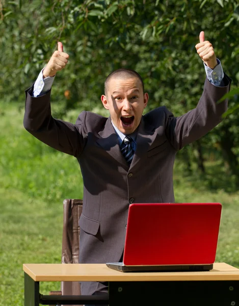 Man with red laptop working outdoors — Stock Photo, Image