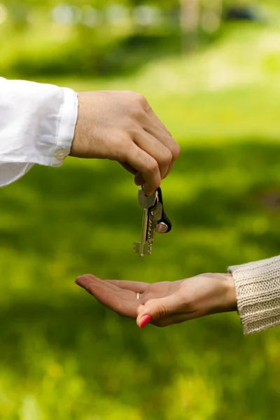 stock image Hands of two , giving and taking keys, isolated over nature background