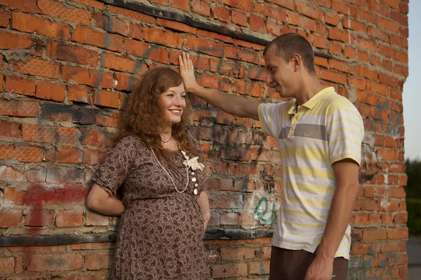Portrait of a happy young man kisses his pregnant wife . outdoor . — Stock Photo, Image