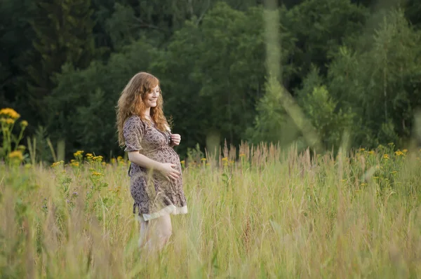 Een zwangere jonge vrouw in een veld — Stockfoto
