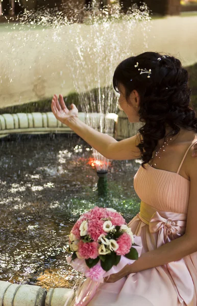 Pięknej narzeczonej z kwiatami przy fontannie — Zdjęcie stockowe