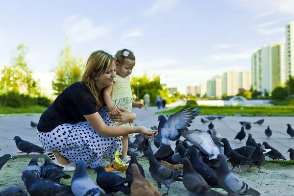 stock image Little girl and mother feeding pigeons urban blue-gray