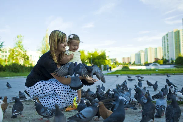 stock image Little girl and mother feeding pigeons urban blue-gray