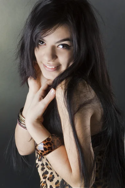 Retrato de uma bela menina bronzeada de cabelos escuros em um fundo preto — Fotografia de Stock