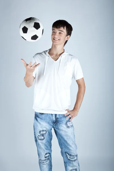 Ung pojke håller foten bollen isolerad på grå bakgrund — Stockfoto
