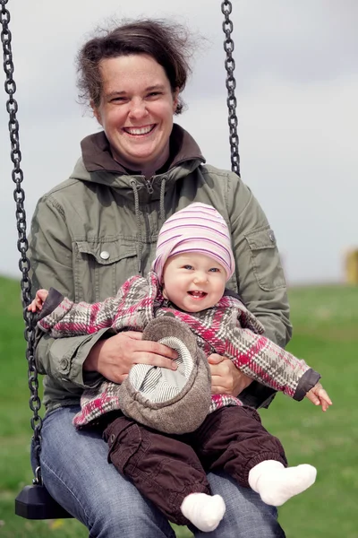 Uśmiechnięta dziewczynka z mamą na huśtawce — Zdjęcie stockowe
