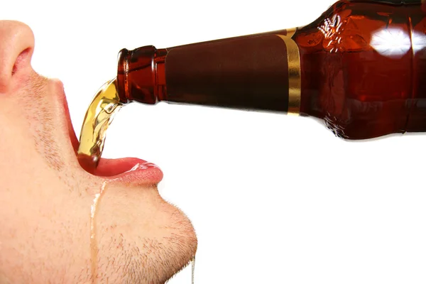 Cerveja está sendo derramada na boca a partir de garrafa — Fotografia de Stock