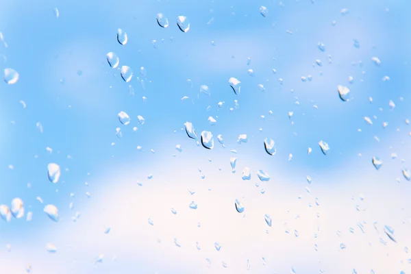 푸른 하늘을 배경으로 유리 위로 물방울이 떨어진다 — 스톡 사진