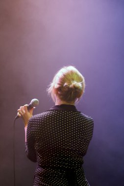 kadın bir mikrofon ile tekrar sahnede