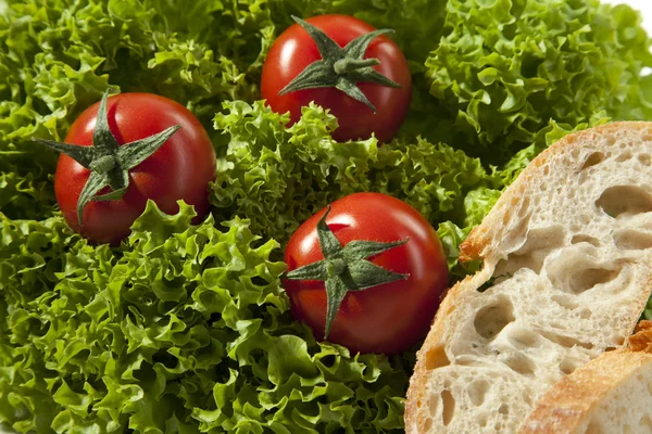 Tre tomater i en sallad Stockfoto