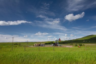 Beautiful landscape with green grass, blue sky and pumpjack. Pho clipart