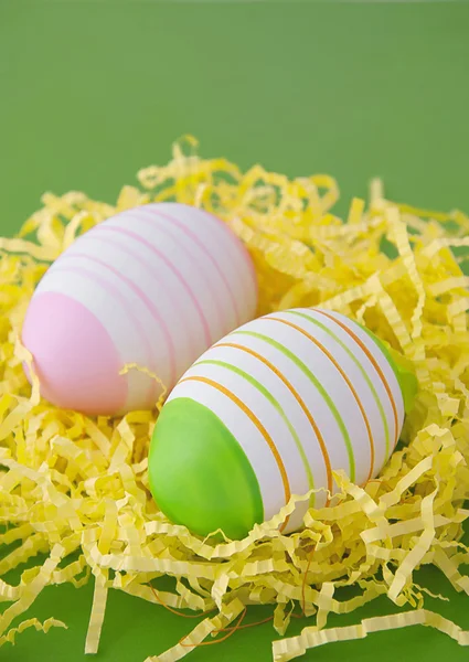 Two easter eggs in yellow nest on green background — Stock Photo, Image