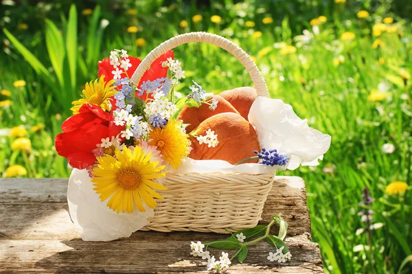 Una canasta con empanadas y flores en el jardín — Foto de Stock