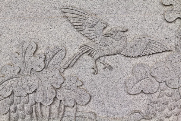 Птица, вырезанная на каменной стене в китайском храме Таиланда Стоковая Картинка