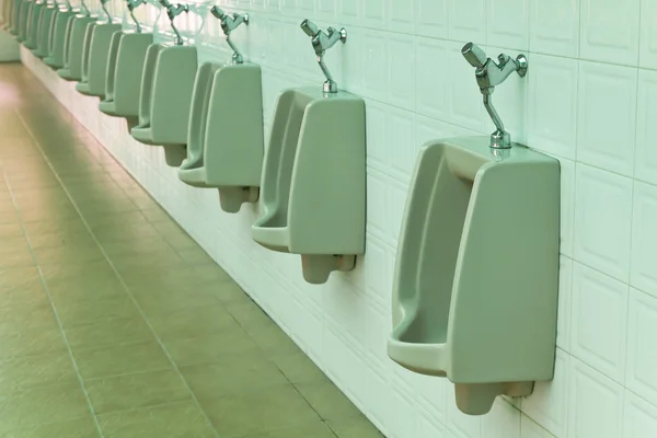 Una fila de urinarios en la pared de baldosas en un baño público —  Fotos de Stock