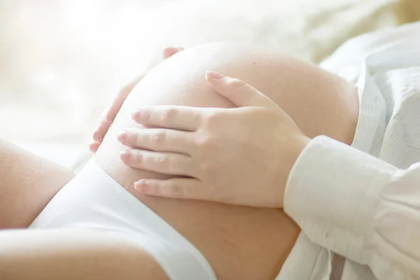 Беременная женщина держит ее — стоковое фото