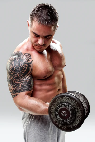 Bodybuilder with a tattoo lifting weights, closeup — Stock Photo, Image