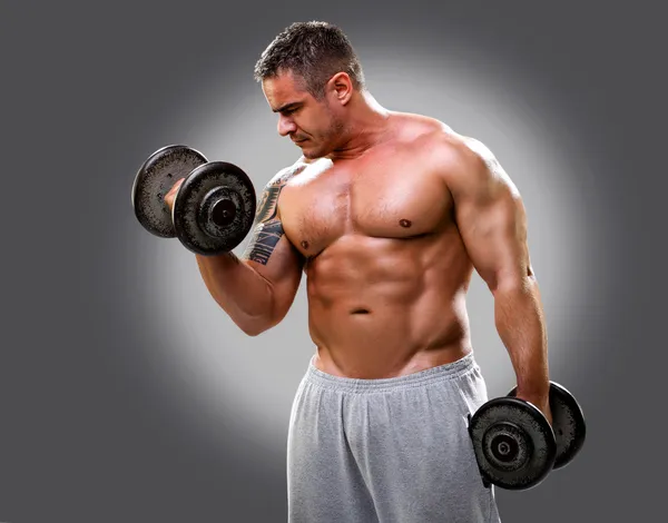 Bodybuilder with a tattoo lifting dumbells, closeup 2 — Stock Photo, Image