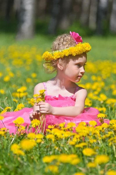 Маленькая девочка стоит на поле одуванчиков — стоковое фото