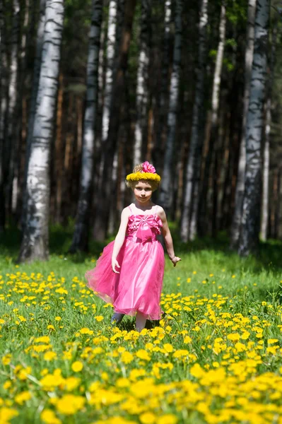 Little girl stands on field of dandelions — Stock Photo, Image
