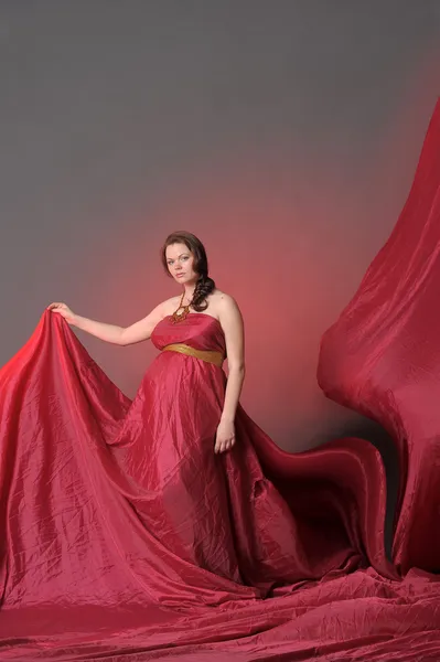Těhotná žena v červeném létající šaty — Stock fotografie