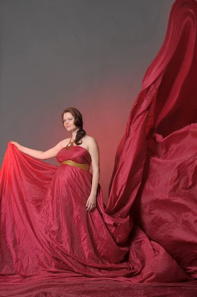 Zwangere vrouw in het rood vliegen jurk — Stockfoto