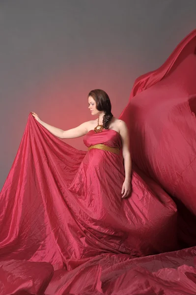 Těhotná žena v červeném létající šaty — Stock fotografie