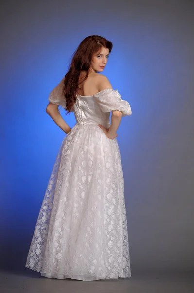 Mooie jonge vrouw in een witte jurk. in de studio. — Stockfoto
