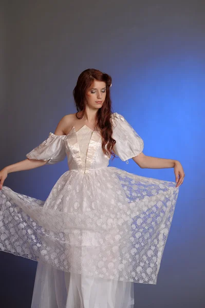 Mooie jonge vrouw in een witte jurk. in de studio. — Stockfoto