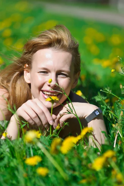 Young pretty woman in wreath of dandelions in the meadow solar day — Zdjęcie stockowe