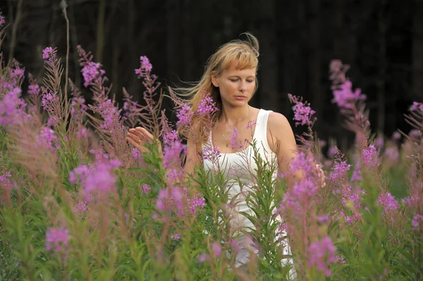 Meisje onder de bloemen in het veld — Stockfoto