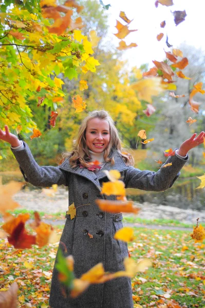 Веселая девушка бросает опавшие листья — стоковое фото