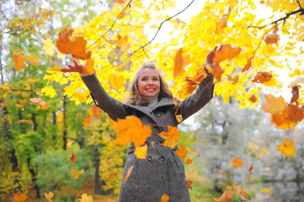 Веселая девушка бросает опавшие листья — стоковое фото