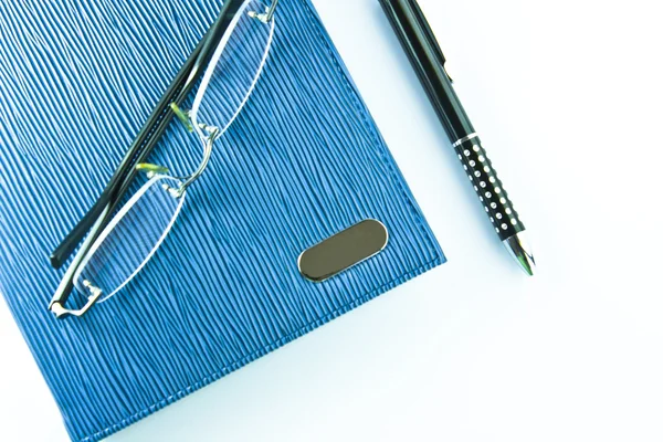 Gafas en cuaderno azul con bolígrafo negro en aislamiento — Foto de Stock