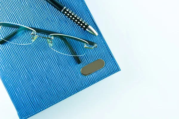 Γυαλιά σε μπλε σημειωματάριο με μαύρο στυλό σε απομόνωση — Φωτογραφία Αρχείου