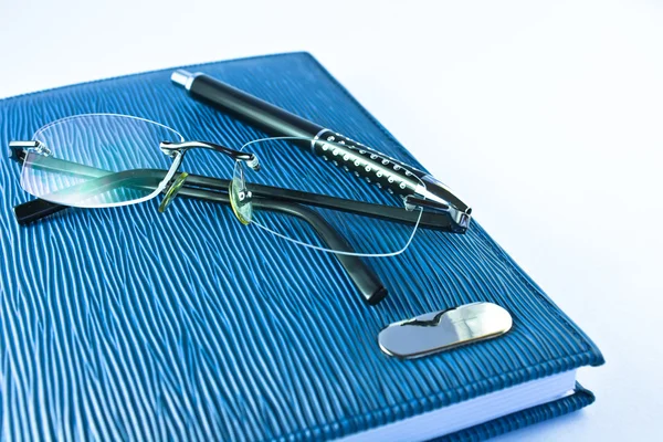 Mavi defter ile siyah kalemi tecrit içinde gözlük — Stok fotoğraf