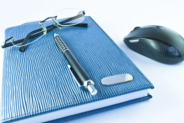 Óculos e caneta preta no caderno azul com mouse em isolamento — Fotografia de Stock